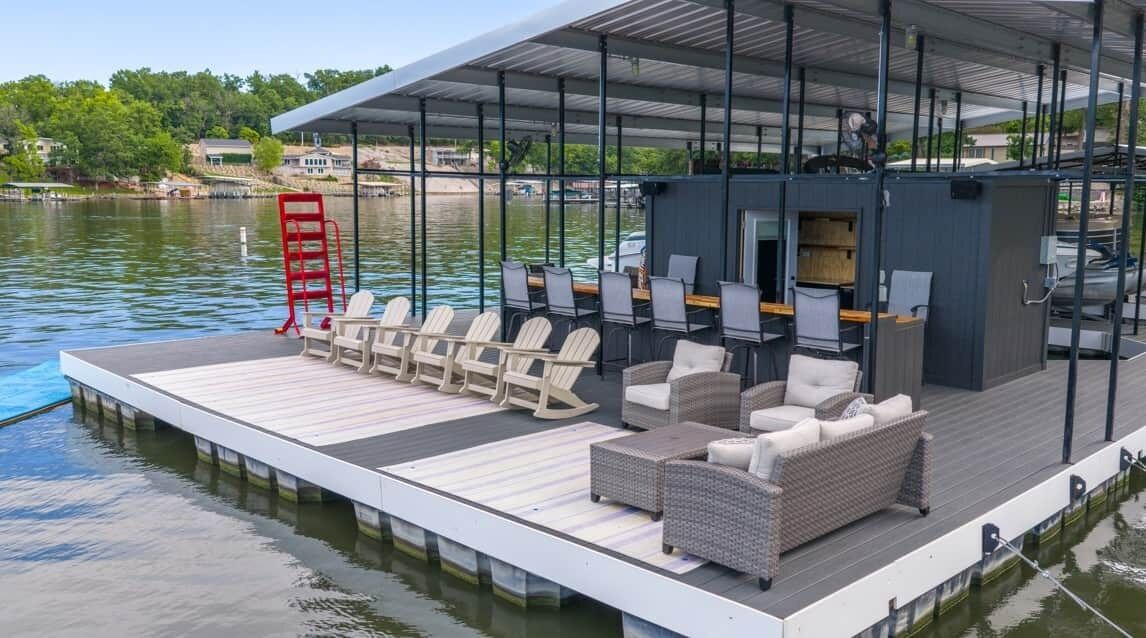 A floating deck with seating and a bar area overlooking a body of water.