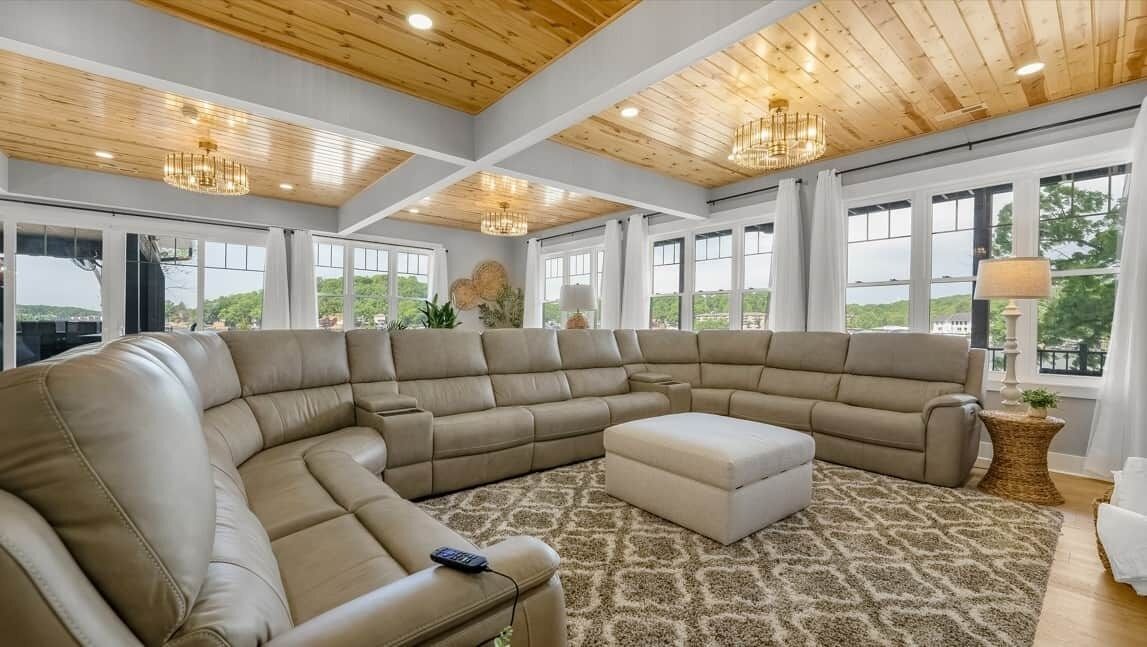 A large L-shaped sectional sofa in a room with a high ceiling and large windows.