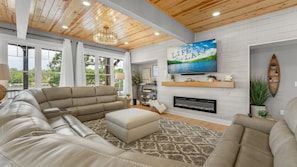 A spacious living room with a large sofa, a fireplace, and a television mounted on the wall. - Hidden Valley Paradise (Glaze Township)