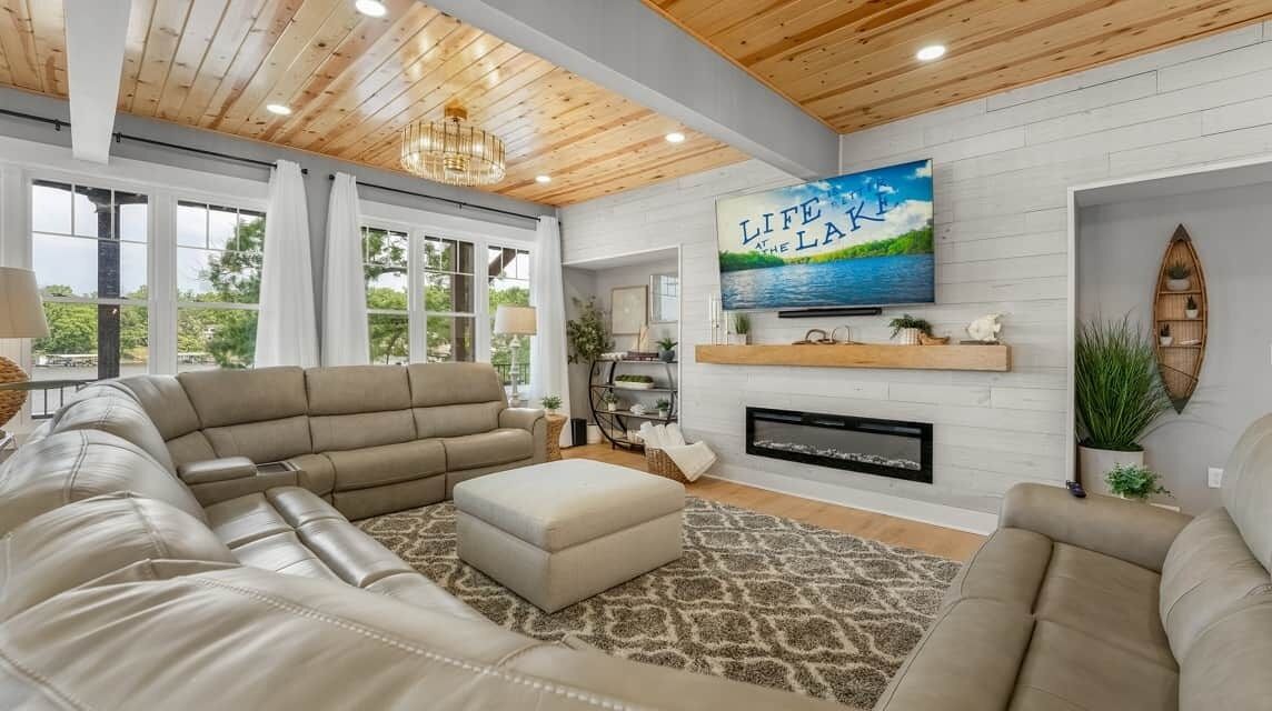 A modern living room with a sectional sofa, a fireplace, and a large TV mounted on the wall.