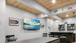 A modern kitchen with a long wooden table, bar stools, and a television mounted on the wall. - Hidden Valley Paradise (Glaze Township)