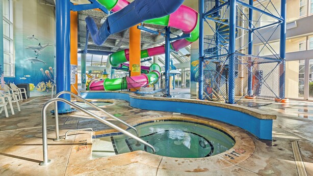 An indoor water park with slides, a pool, and a mural of marine life.