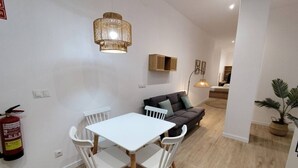 En moderne stue med et hvidt bord og stole, en mørk sofa og en hængende lampe.