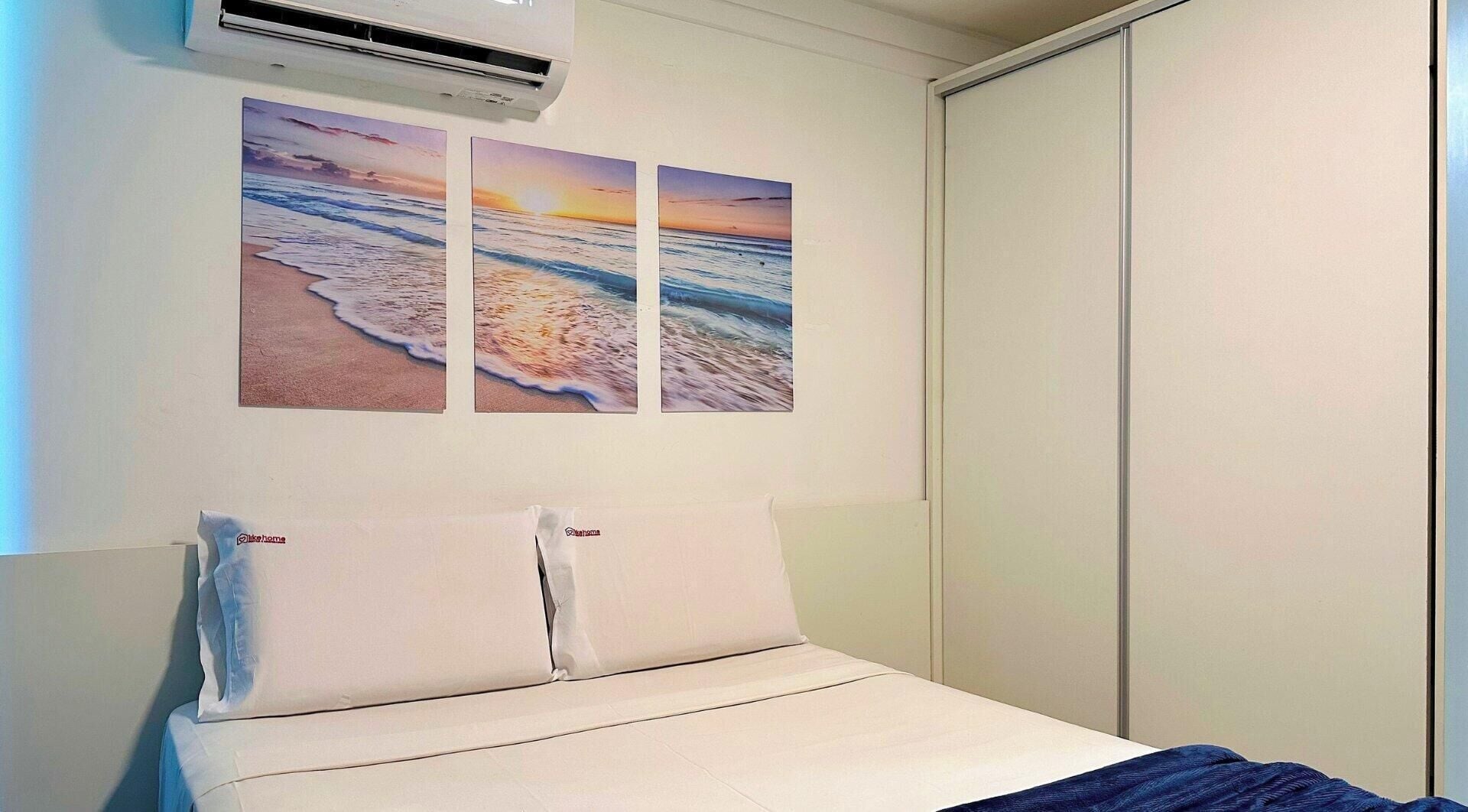 A bedroom with a bed, two pillows, and a wall-mounted air conditioner.