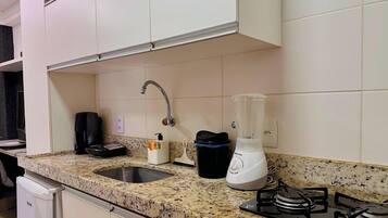 Una cocina con encimera de granito, un fregadero, cafetera, licuadora y estufa.