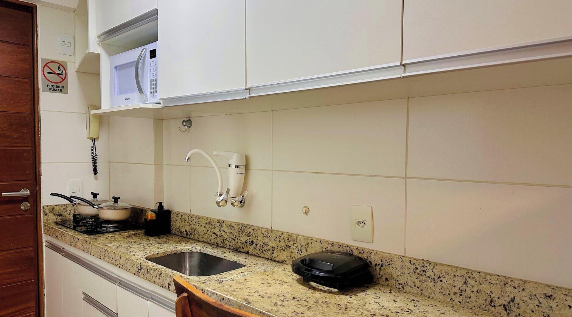 A kitchen with a granite countertop, a sink, a stove, and a microwave.