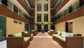 Un atrium moderne avec des meubles en osier et des plantes en pot.