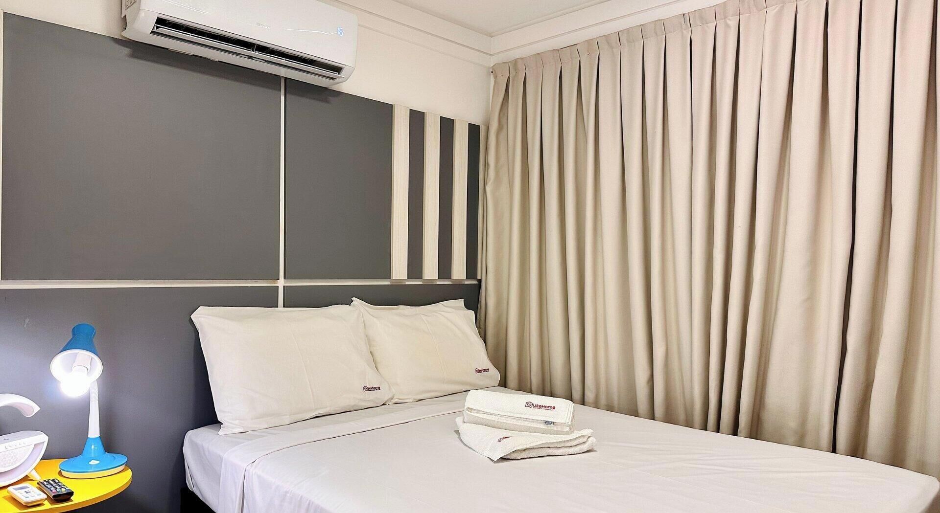 Hotelkamer met een bed, een bedlampje, een opgevouwen handdoek en een wandairconditioner.