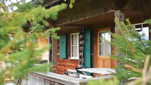 A wooden cabin with a porch, a table, and chairs.