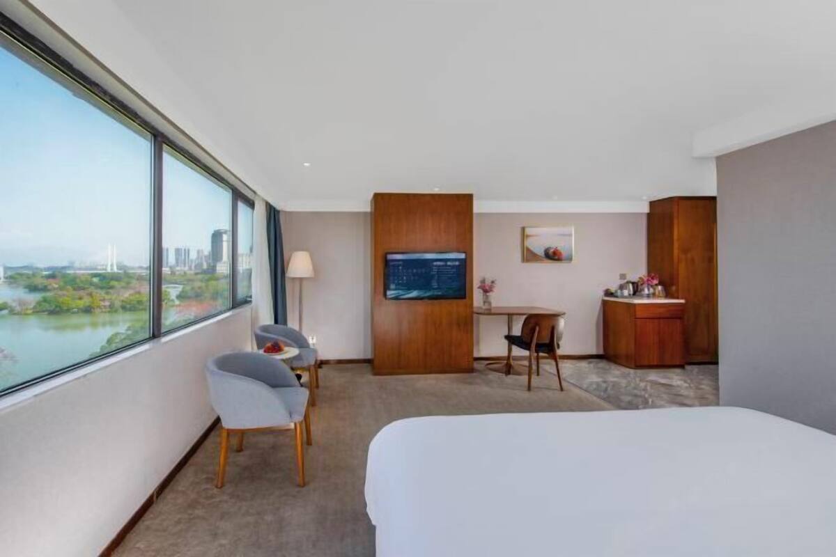 Una habitación de hotel con un ventanal grande, una cama, un escritorio y una silla.
