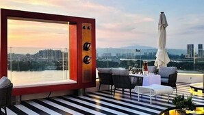A rooftop terrace with a panoramic city view, a red-framed window, and a striped floor. - West Lake Garden Hotel (Huizhou)
