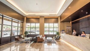 A spacious lobby with a reception desk, seating area, and large windows offering a view of the street. - West Lake Garden Hotel (Huizhou)