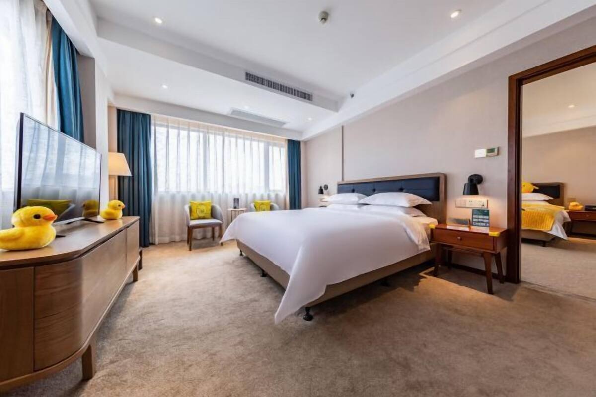 Una habitación de hotel con una cama grande, un escritorio con televisor de pantalla plana, una silla y un aparador.
