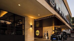A hotel entrance with a modern design, featuring a large sign with Chinese characters, a well-lit facade, and a car parked outside. - West Lake Garden Hotel (Huizhou)