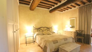 A bedroom with a bed, bedside tables, a dresser, a chair, and a mirror.