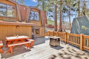 Una terraza de madera con mesas de picnic y una chimenea.