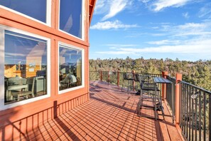 Una terraza de madera con barandilla metálica, con vista a un área boscosa.