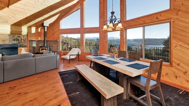 A spacious living area with a fireplace, a dining table with chairs, and large windows offering mountain views.