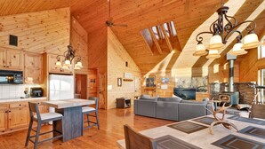 A spacious log cabin interior with a kitchen, dining area, and living room.