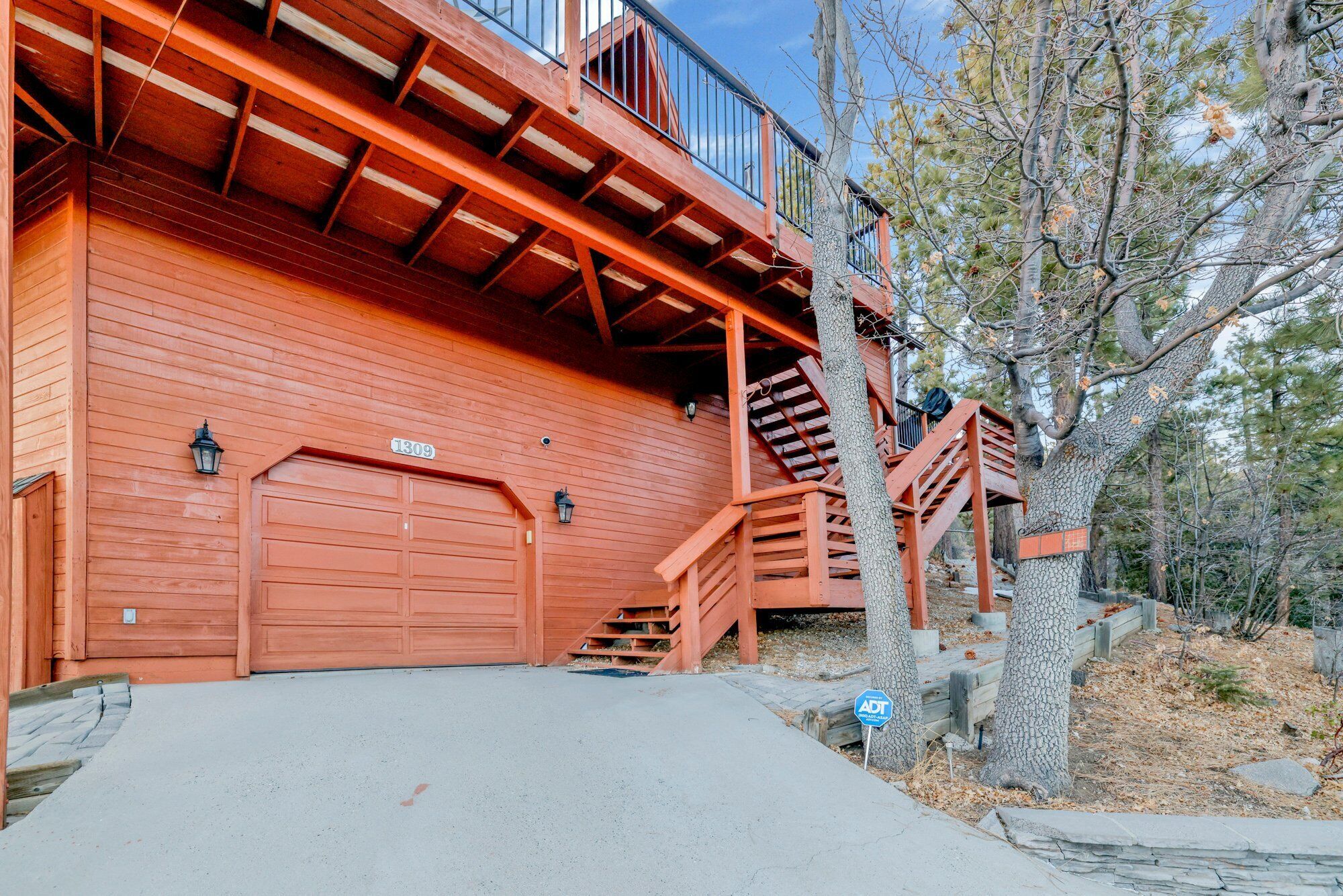 Een tweelaags houten gebouw met garage, een trap en een balkon.