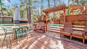 A wooden deck with outdoor seating, a pergola, and a covered area with a table and chairs. - Green Squirrel Chateau #2484 (Big Bear Lake)