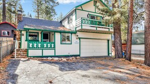 A two-story building with a green and white exterior, a garage, and a small porch with decorative elements. - Green Squirrel Chateau #2484 (Big Bear Lake)