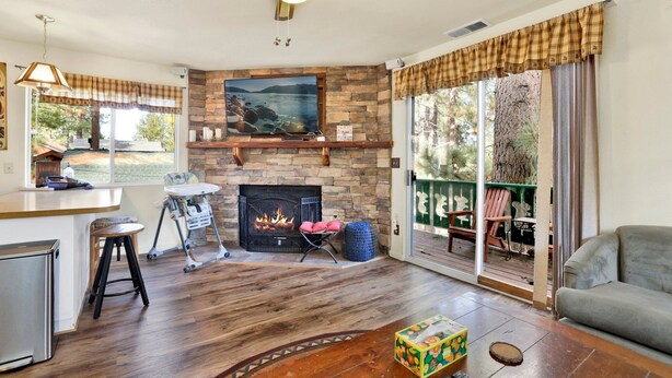 A living room with a fireplace, a dining area, and a view of the outdoors. - Green Squirrel Chateau #2484 (Big Bear Lake)