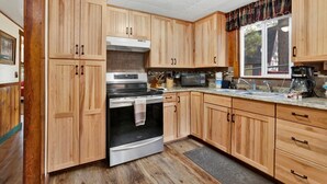 A kitchen with wooden cabinets, a stainless steel oven, a microwave, and a coffee maker. - Green Squirrel Chateau #2484 (Big Bear Lake)