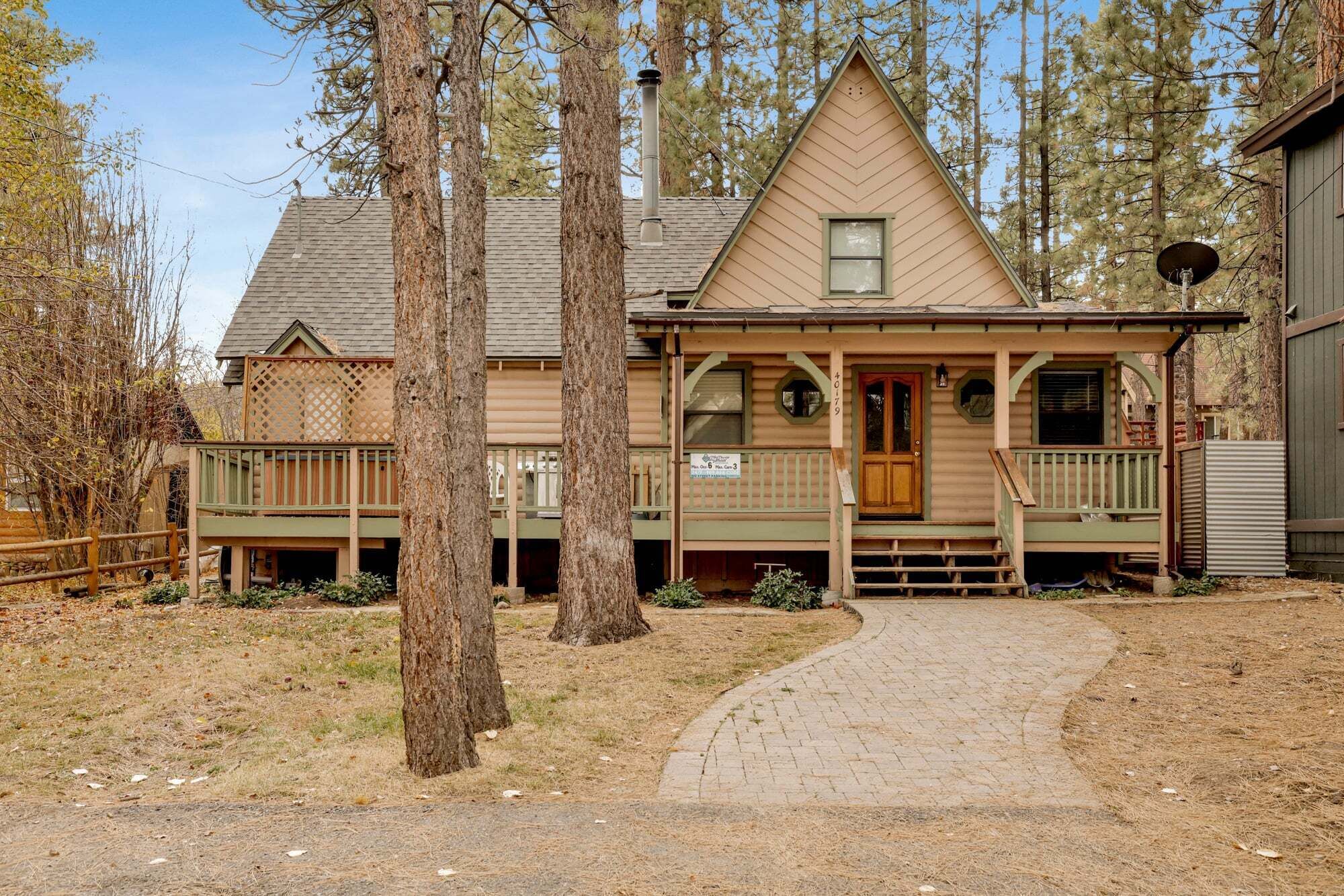 A two-story house with a front porch, a chimney, and a driveway leading to the entrance.