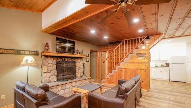 Una sala de estar acogedora con chimenea de piedra, sofás de cuero y una escalera de madera que lleva a una cocina.