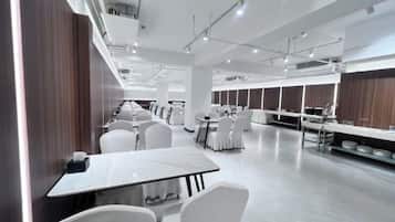 A modern dining area with white chairs and tables, a long counter with a display, and a wooden wall.