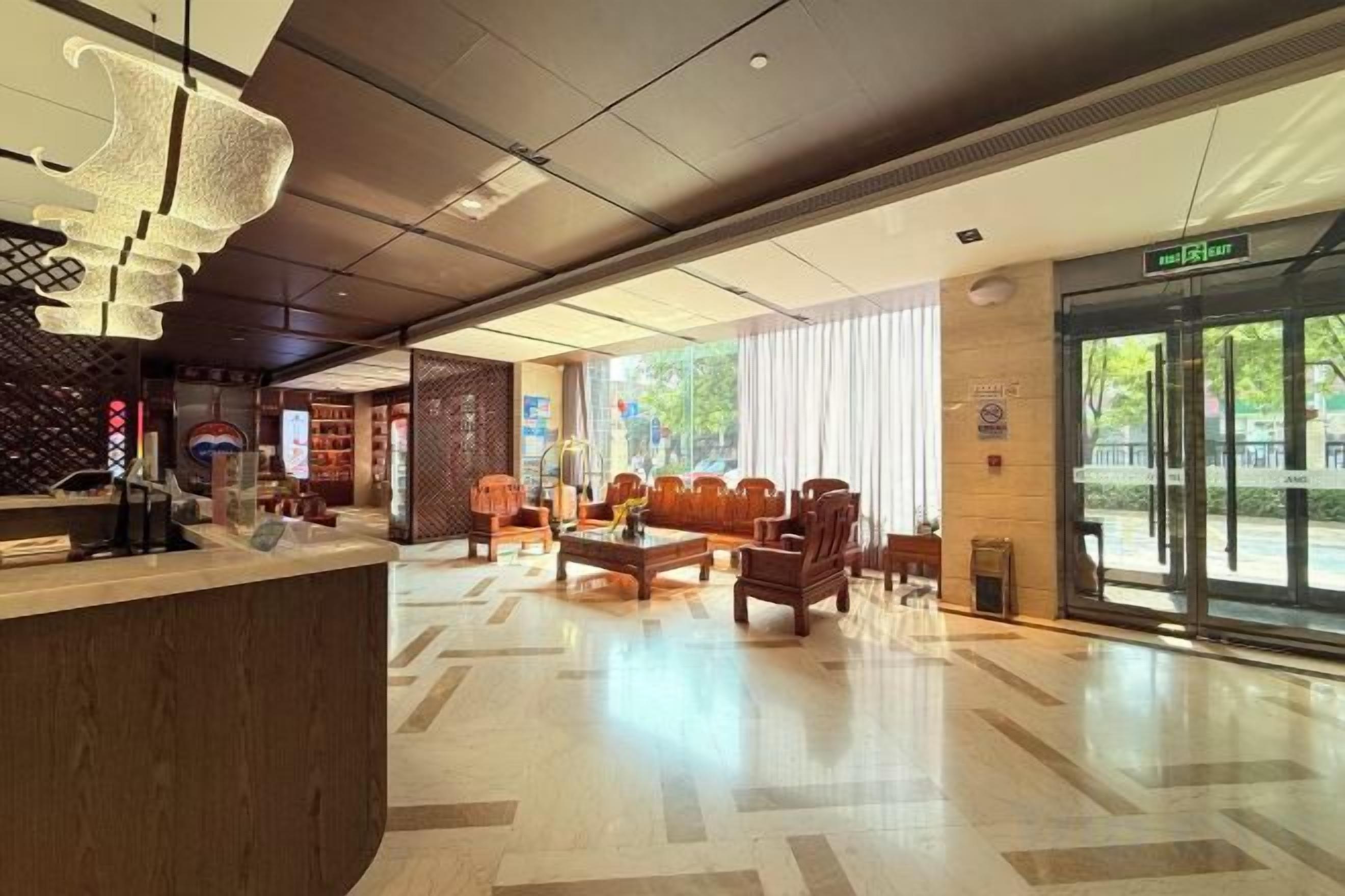 Un vestíbulo de hotel con mostrador de recepción, zona de estar y ventanas amplias.