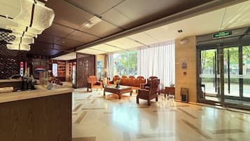 Un vestíbulo de hotel con mostrador de recepción, zona de estar y ventanas amplias.