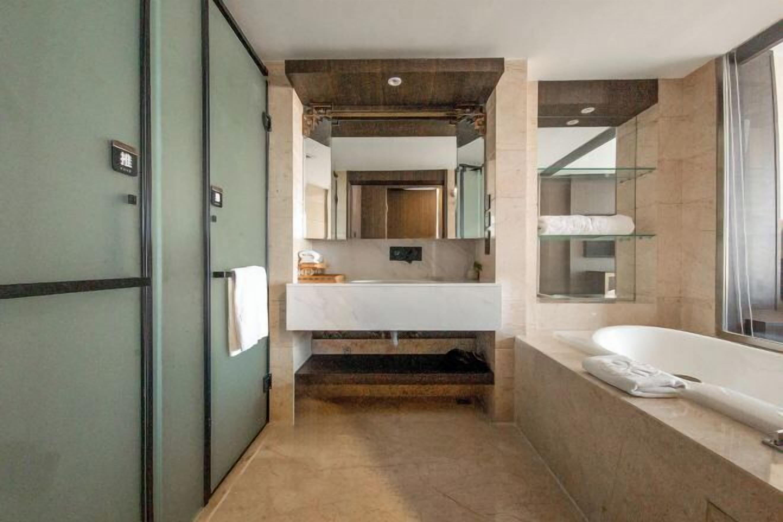 A modern bathroom with a large mirror, a white sink, a bathtub, and a glass shower enclosure.
