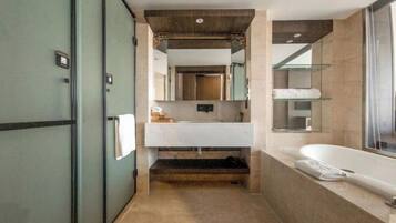 A modern bathroom with a large mirror, a white sink, a bathtub, and a glass shower enclosure.