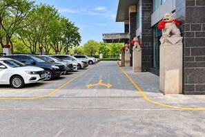 A parking lot with cars parked in rows, a building entrance with a lion statue, and a clear sky. - Rishengchang Hotel (Beijing South Railway Station) (Beijing)