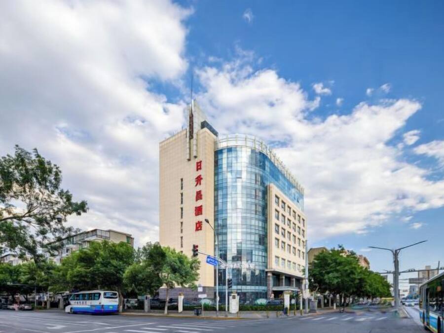 Un hôtel moderne avec une façade en verre incurvée, une enseigne verticale bien visible et un ciel d’un bleu éclatant.