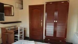 A hotel room with a bed, a desk, a chair, a wardrobe, and a mirror. - Villas Coliving Casa Rural (Sant Fost de Campsentelles)