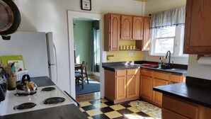 Une cuisine avec un carrelage à motifs, des placards en bois, une cuisinière et une fenêtre avec des rideaux.