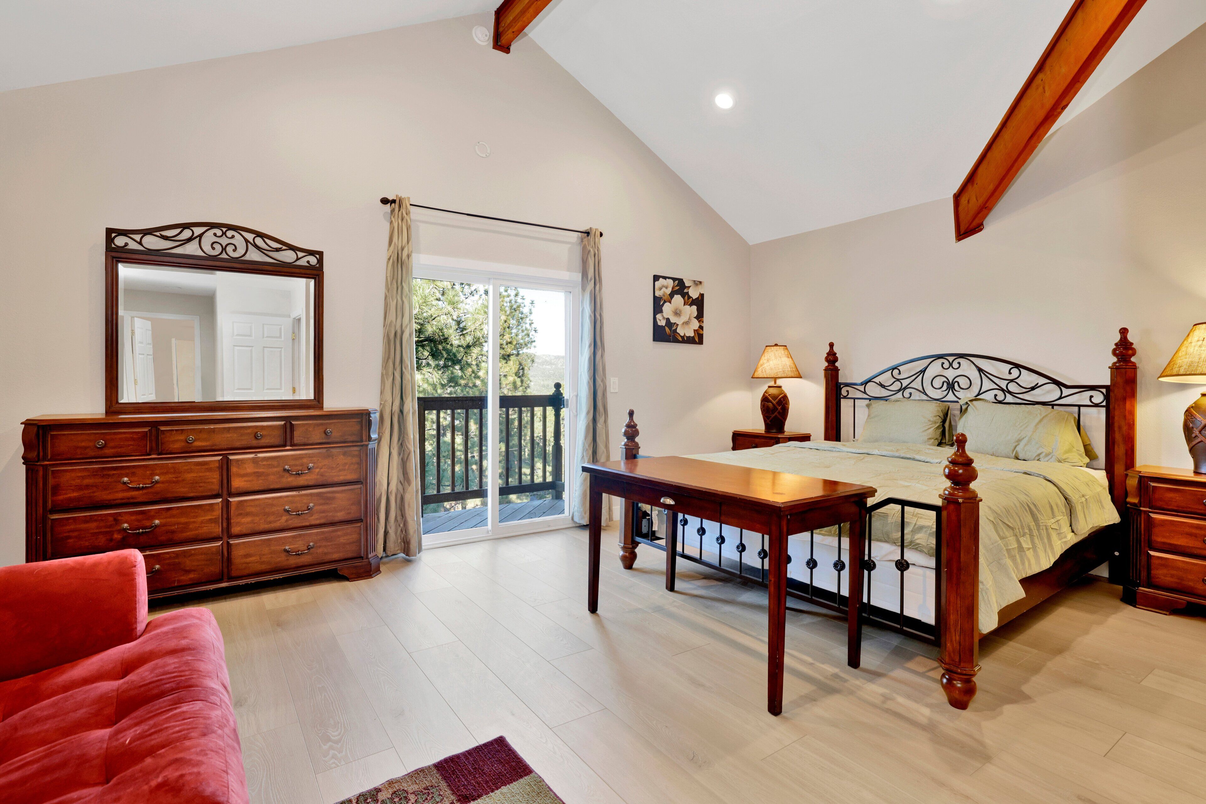 A bedroom with a bed, dresser, and a large mirror.