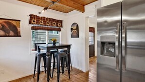 A kitchen with a stainless steel refrigerator, wooden ceiling, and a window with a view of a balcony. - Camp Conklin #2337 (Big Bear Lake)