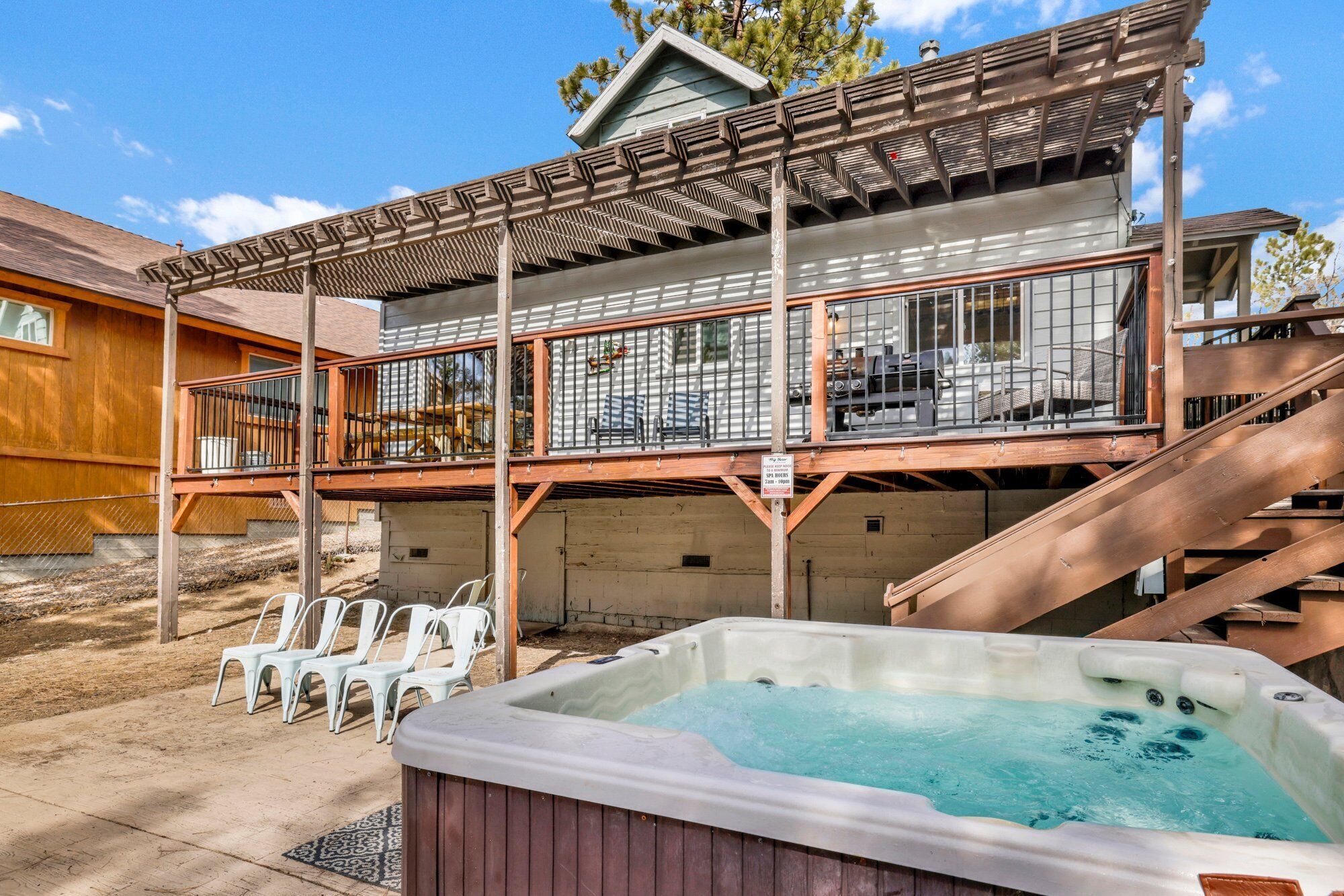 A two-story building with a hot tub, outdoor seating, and a covered deck.
