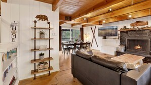 A cozy living room with a fireplace, wooden beams, a sofa, and a TV. - Camp Conklin #2337 (Big Bear Lake)