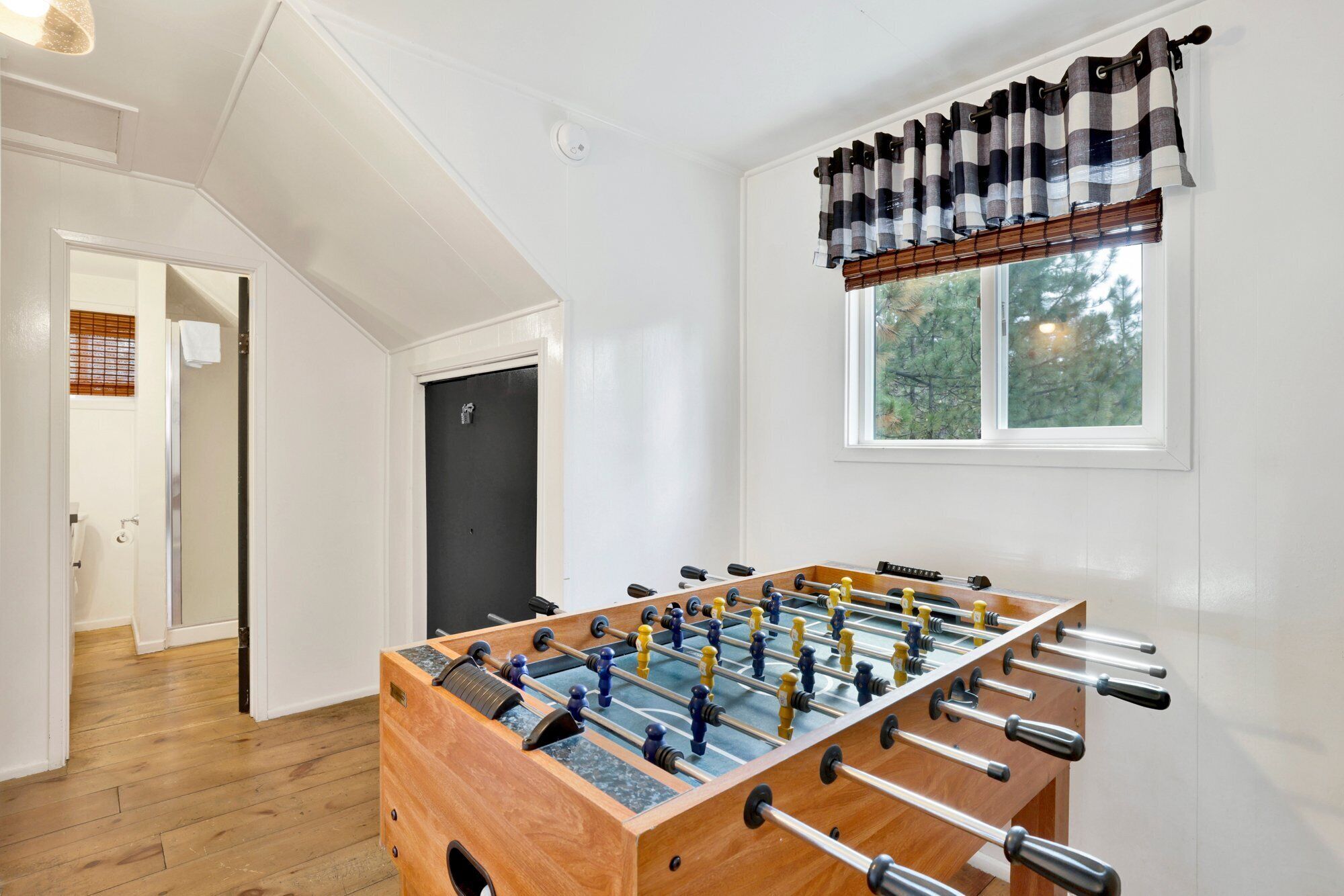 Ein Zimmer mit Kicker, einem Vorhangfenster und einer Tür.