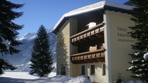 A building labeled "haus kauner apartments" with a balcony, surrounded by snow-covered trees and mountains in the background. - Haus Kaunergrat (Kaunertal)