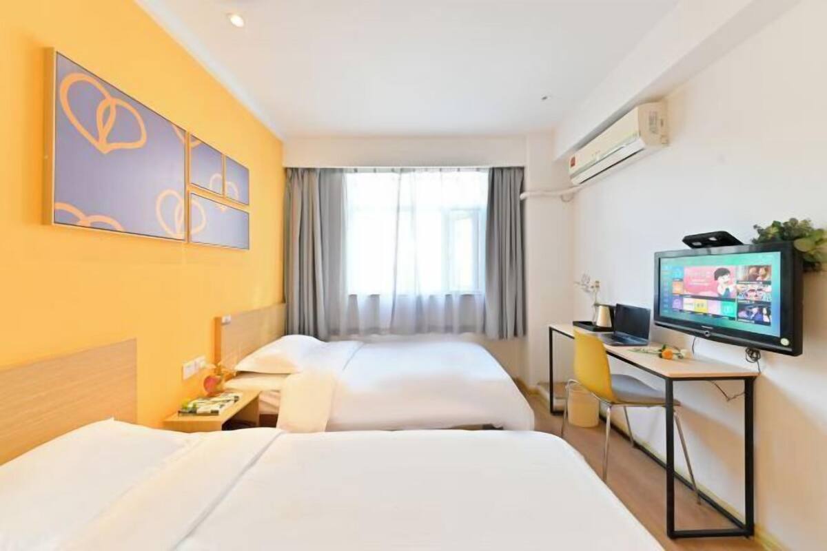 A hotel room with two beds, a desk with a computer, and a TV.
