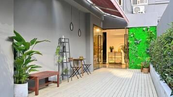 Um pátio moderno ao ar livre com deck de madeira, um banco e vasos com plantas.