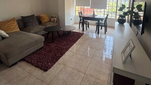 A modern living room with a sofa, coffee table, and dining area.