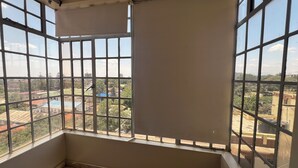 A room with a large window offering a view of a residential area.