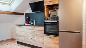 A modern kitchen with wooden cabinetry, a built-in oven, a microwave, and a stainless steel refrigerator. - L'Ecureuil apartment, Finnish bath on the edge of the forest. Pets allowed (Gérardmer)